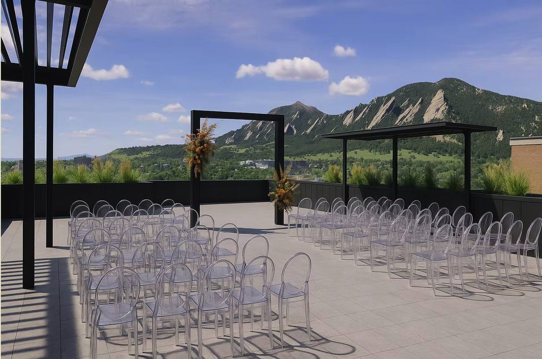 Rooftop ceremony at VUE/boulder with clear ghost chairs and the Flatirons behind the arch